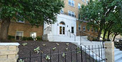 a large brick building with stairs and trees in front of it