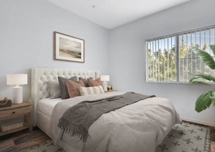 A bedroom with a large bed and a window with a view of trees. at Maryland Villas Apartments, Las Vegas, NV, 89101