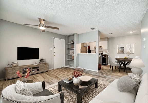A living room with a white couch, a black coffee table, and a flat screen TV.