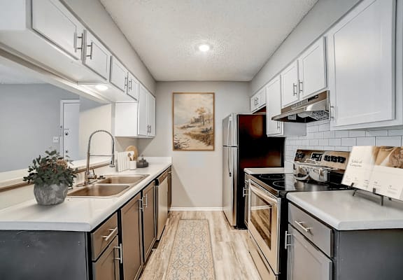 A kitchen with a sink, oven, and refrigerator.