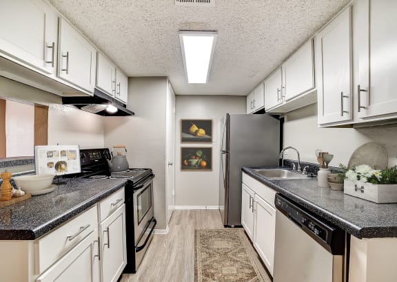 a kitchen with white cabinets and black countertops