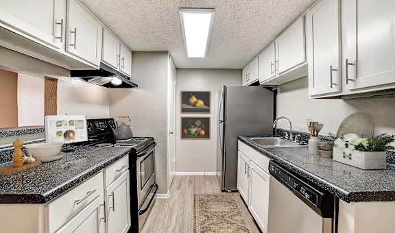 a kitchen with white cabinets and black countertops