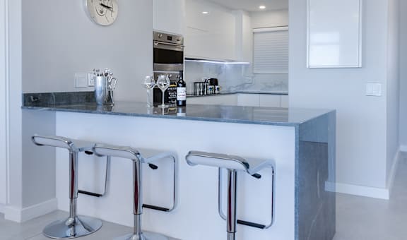 a kitchen with a long counter and three stools in front of it
