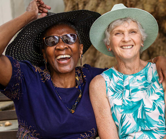 Three women are laughing together in front of a tree.