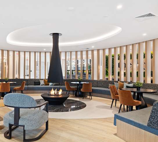 the lobby of a hotel with chairs and tables and a fireplace