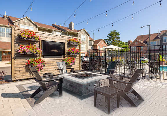 a patio with a fire pit and chairs and a fence