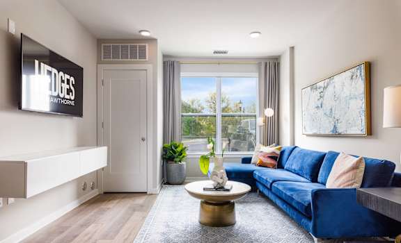 A living room with a blue couch and a flat screen TV mounted on the wall.