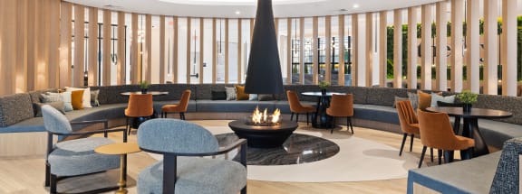 the lobby of a hotel with chairs and tables and a fireplace