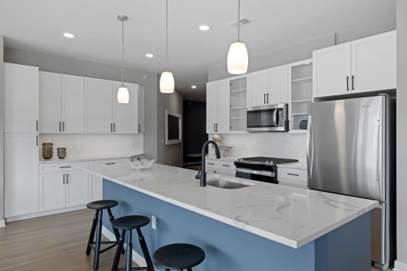 a kitchen with white cabinets and a large island with three stools