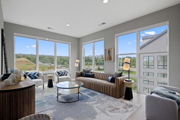 a living room with couches and chairs and large windows