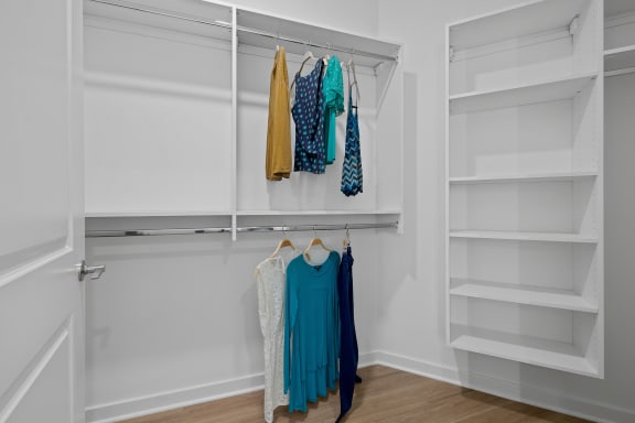 a walk in closet with white closet doors and clothes hanging on a rack