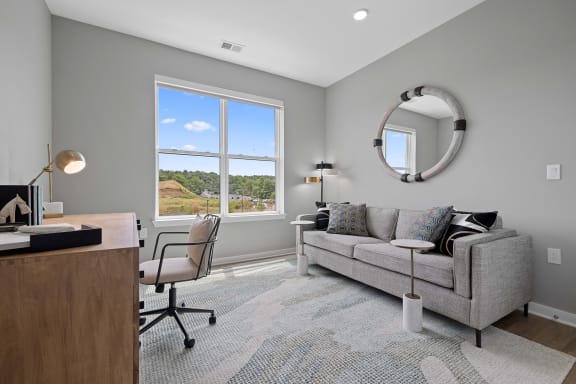 a living room with a couch and a desk with a window
