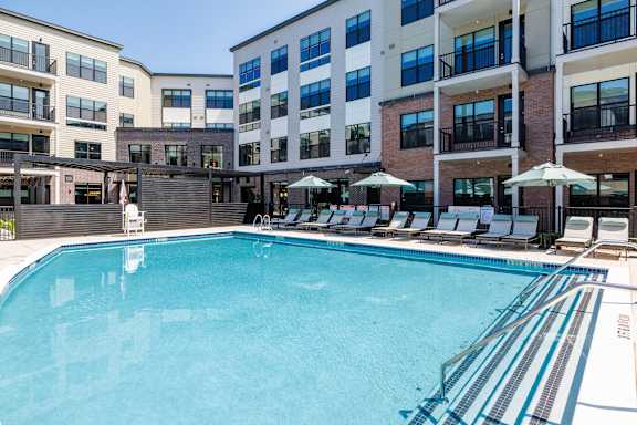 A large swimming pool in front of a multi-story apartment building.