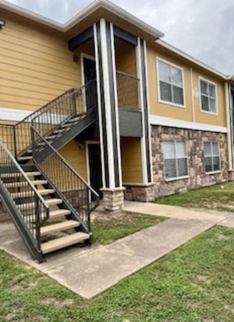 a yellow house with stairs and a porch