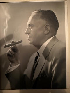A man in a suit smokes a cigar.