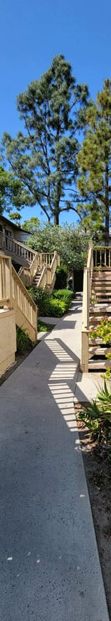 a path leading up to a building with stairs and trees in the background