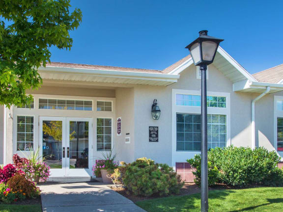 the front of a white house with a sidewalk and a lamp post  at Oakstone Apartments, Utah, 84015