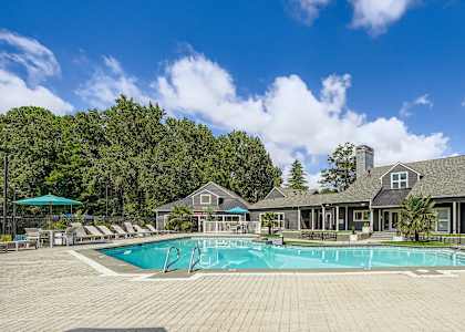 A large outdoor swimming pool surrounded by a paved patio and a building in the background.