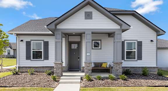A house with a grey front and a brown bench.