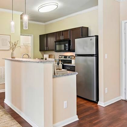 A kitchen with a refrigerator, microwave, and oven.