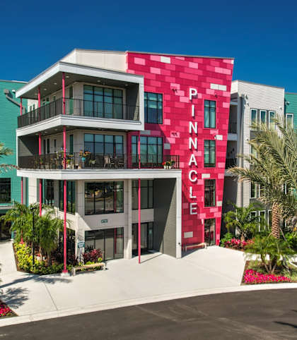 a building with a red facade and palm trees in front of it