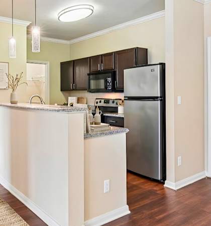 A kitchen with a refrigerator, microwave, and oven.