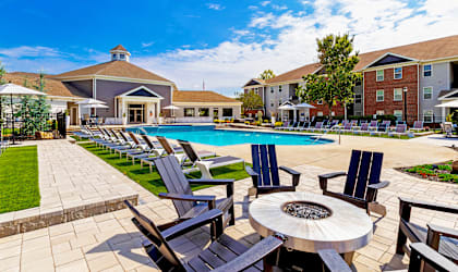 A poolside area with chairs and a fire pit.