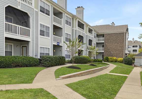 an exterior view of an apartment building with walkways and grass