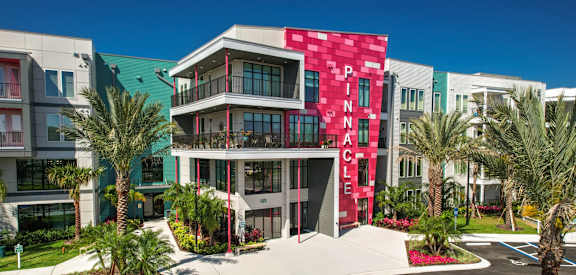 a building with a red facade and palm trees in front of it