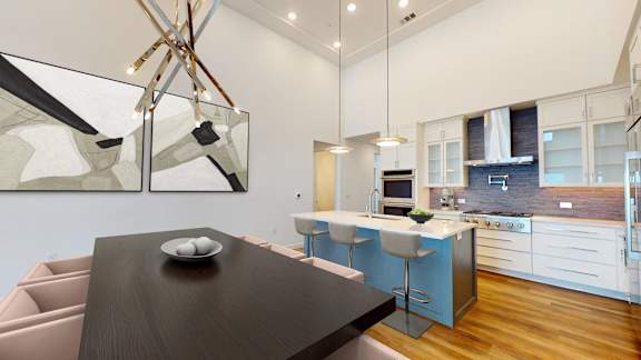 a kitchen and dining room with a black dining table and a blue kitchen