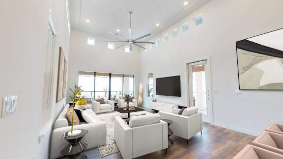 a living room with white couches and chairs and a tv
