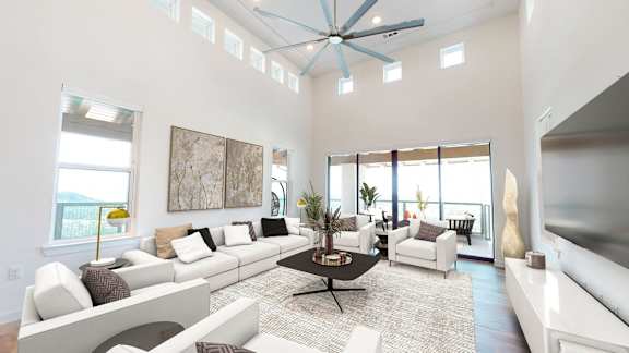 a living room with white furniture and a ceiling fan