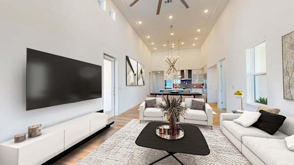 a living room with white furniture and a tv on the wall
