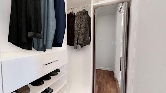 a walk in closet with a mirror and some clothes hanging on the wall