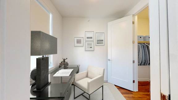 a living room with a desk and chair and a door to a closet