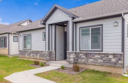 A house with a grey siding and a stone wall.