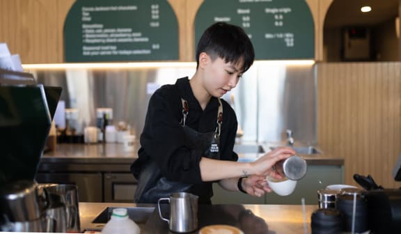 a young boy making a cup of coffee at a coffee shop