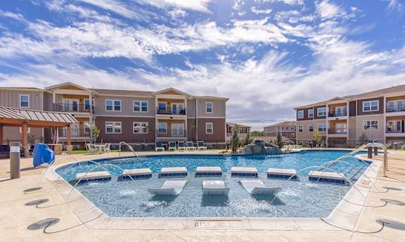 A large outdoor pool with a hot tub in the middle of it.