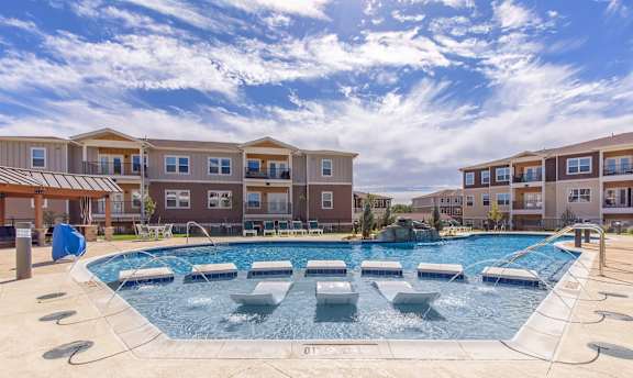 A large outdoor pool with a hot tub in the middle of it.
