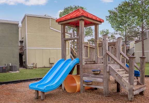 a playground with a blue slide and a wooden structure