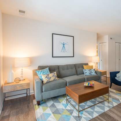 A living room with a grey couch, a blue chair, a coffee table, and a bookshelf