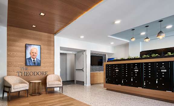 a lobby with two chairs and a desk with a poster of the throop