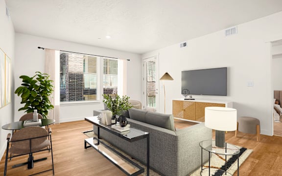 A living room with a grey couch and a television on the wall.