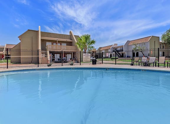 A swimming pool in front of a building with a fence around it.
