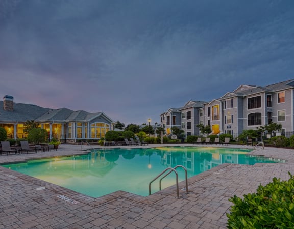 Courtney Station - Resort-style pool and apartment building exterior at dusk