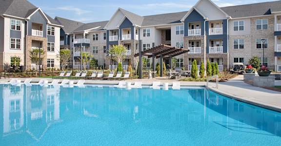A large swimming pool in front of apartment buildings.