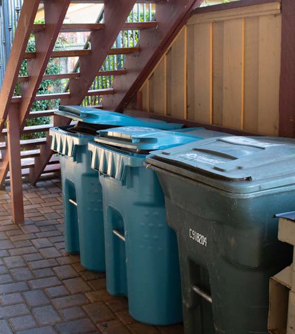 A long hallway with a staircase and garbage bins.