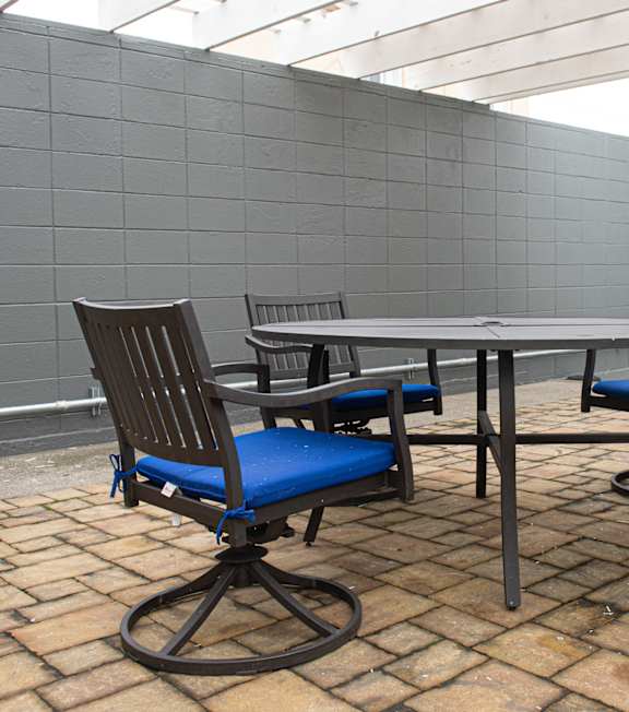 A table and four chairs with blue cushions are set up on a patio.