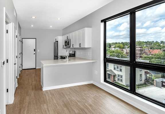 an empty living room with a large window and a kitchen
