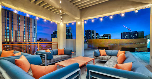 A rooftop patio with blue couches and orange pillows at The Rey Downtown, Phoenix, 85003